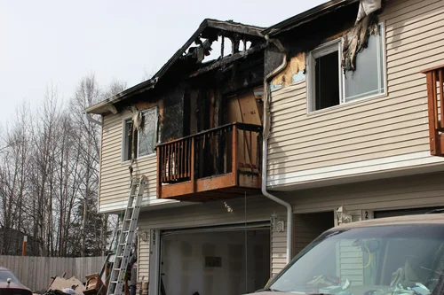 Fire-damaged home exterior with charred siding and structure