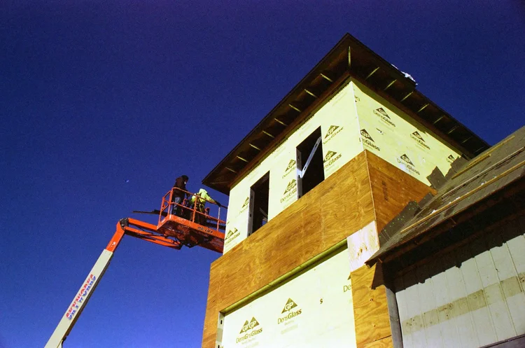 Building exterior under construction with scaffolding and siding installation