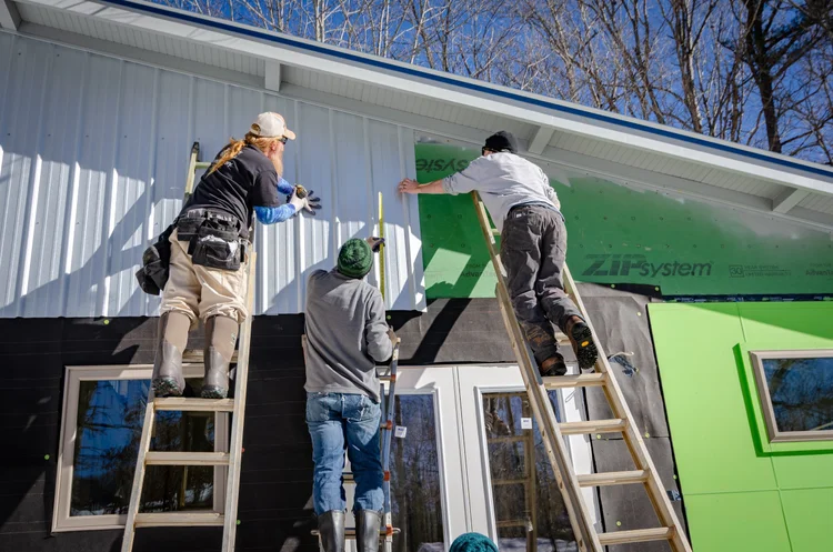 Technicians working on home exterior during restoration or repair project